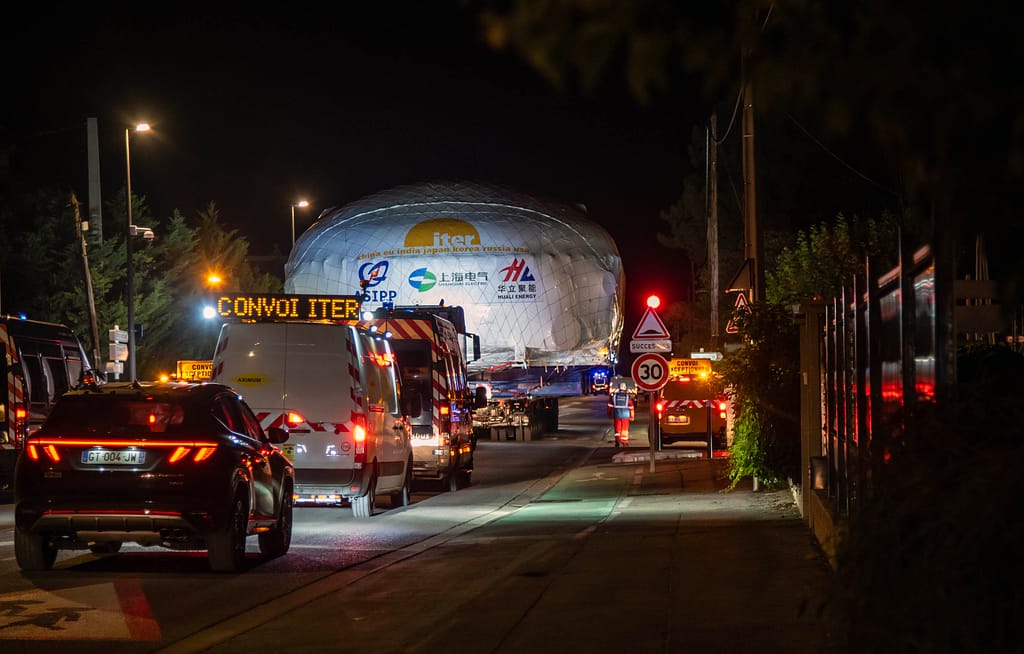 La traversée de villages, comme ici dans la petite ville de Berre-l'Étang lors de la première étape du voyage, est l'une des phases les plus délicates du transport. Lampadaires, panneaux de signalisation et arrêts de bus doivent être démontés temporairement avant le passage du convoi, puis réinstallés immédiatement après. © ITER